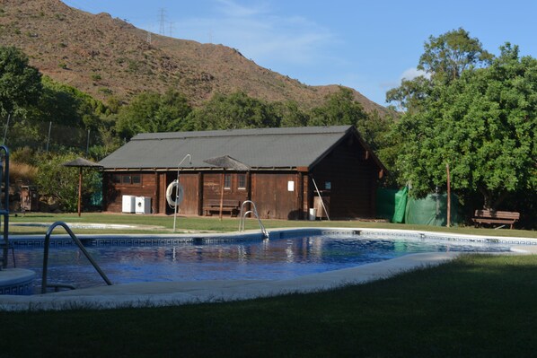 Un edificio de madera rústica con una piscina delantera.