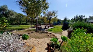 A garden with a stone pathway, benches, and various plants. - Bungalows Los Pedregales (Estepona)