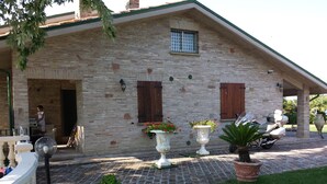 A stone building with a covered porch, potted plants, and a motorcycle. - Villa Giardino degli Eventi (Fano)