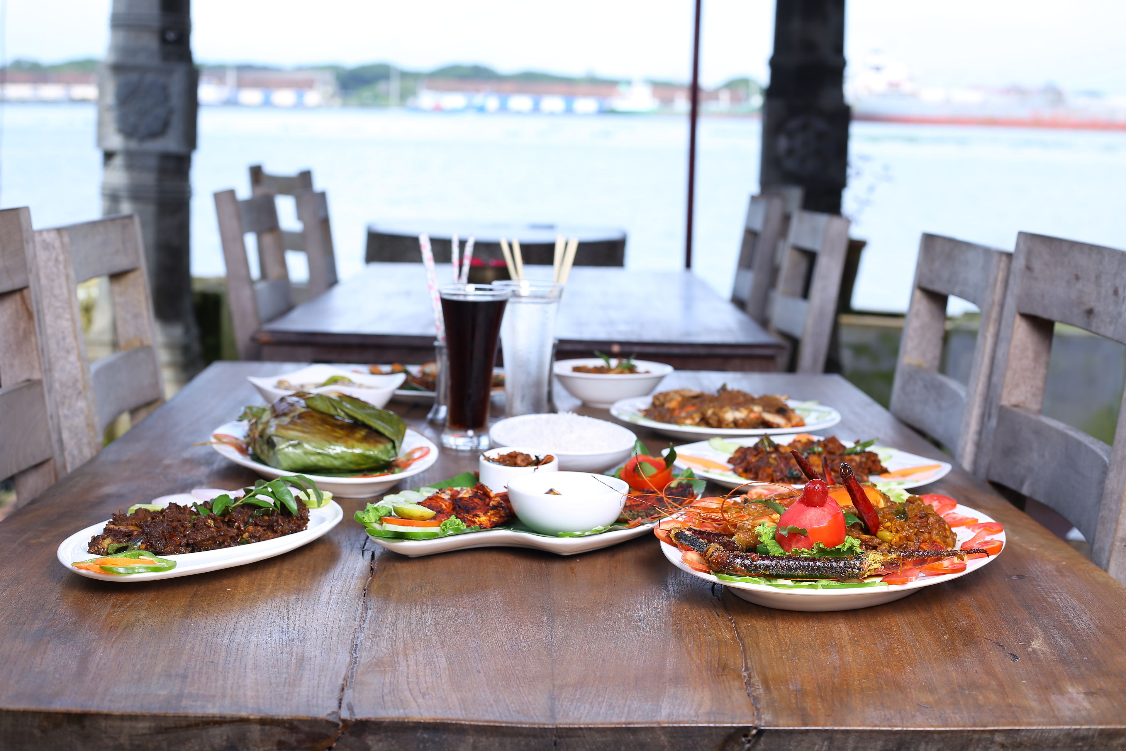 A wooden table with various dishes, including seafood and vegetables, set for a meal.