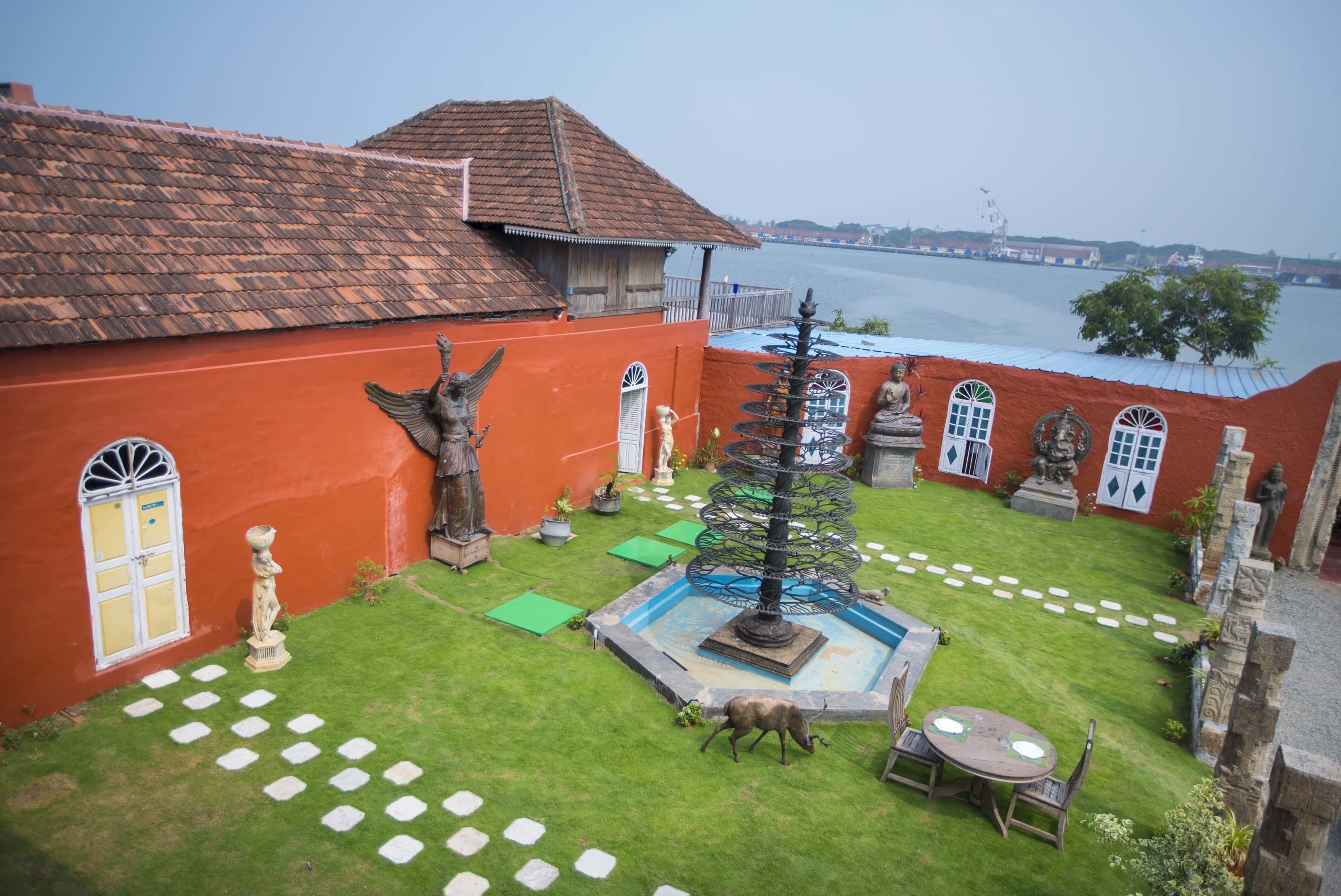 A courtyard with a fountain, statues, and a view of the water.