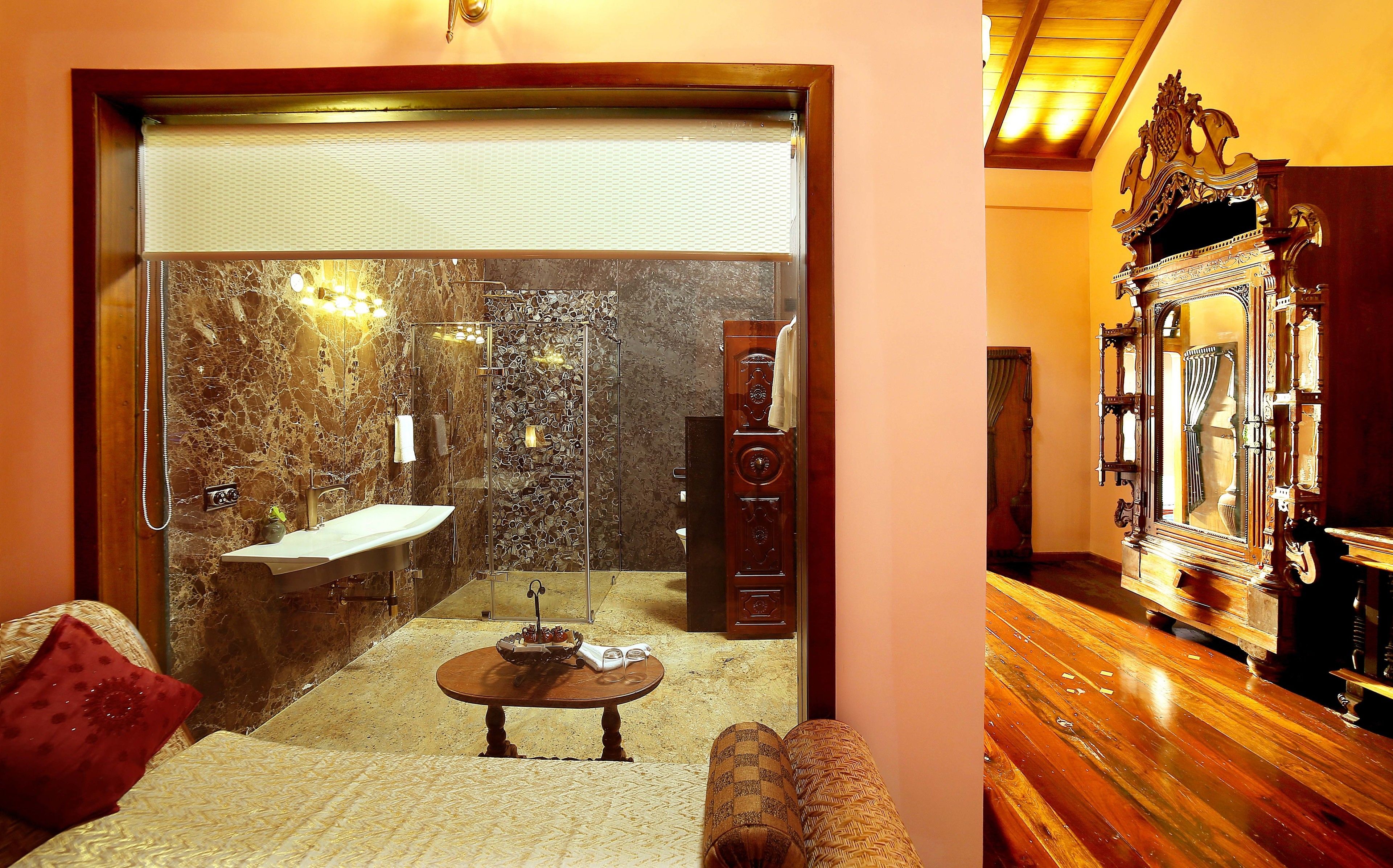 A bathroom with a marble wall, a sink, a shower, and a wooden vanity.