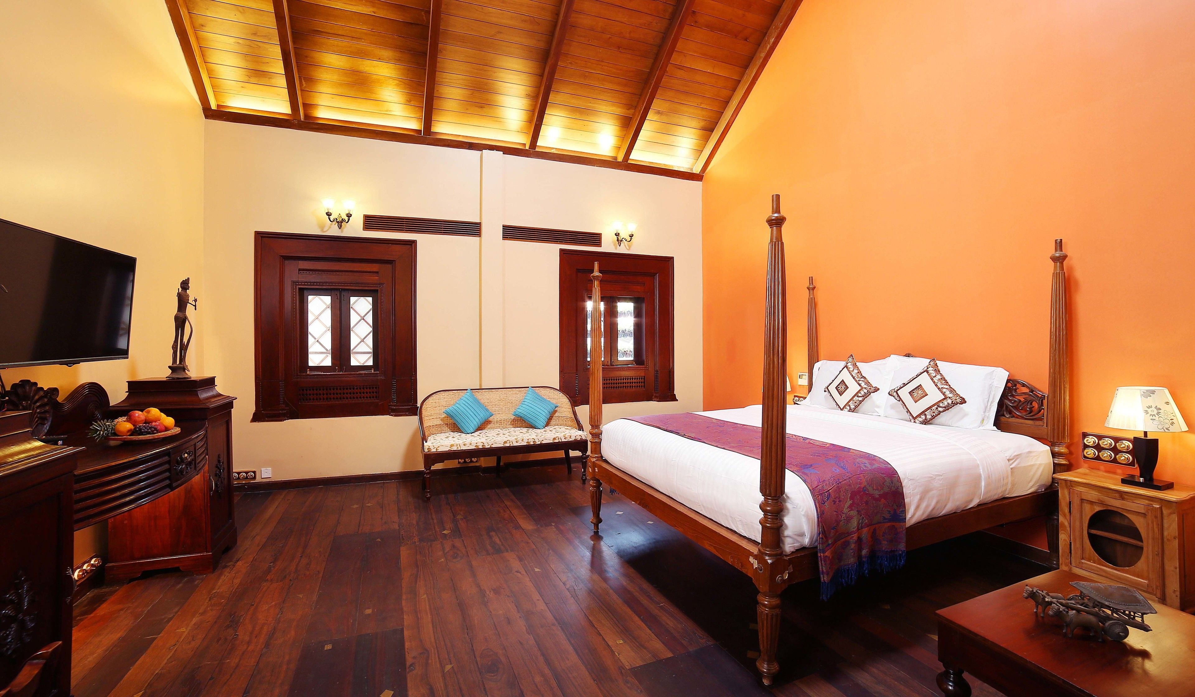 A traditional room with a four-poster bed, wooden furniture, and a television.