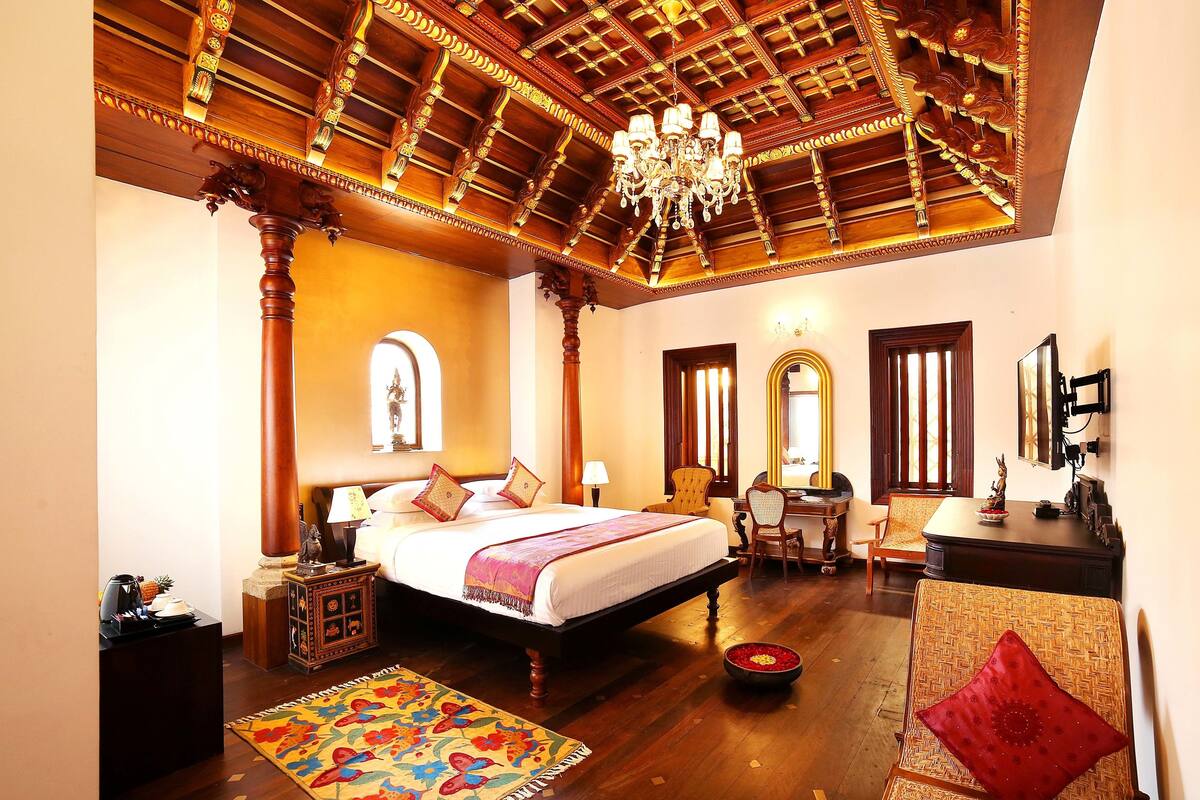 A spacious bedroom with a large bed, a chandelier, and a wooden ceiling.