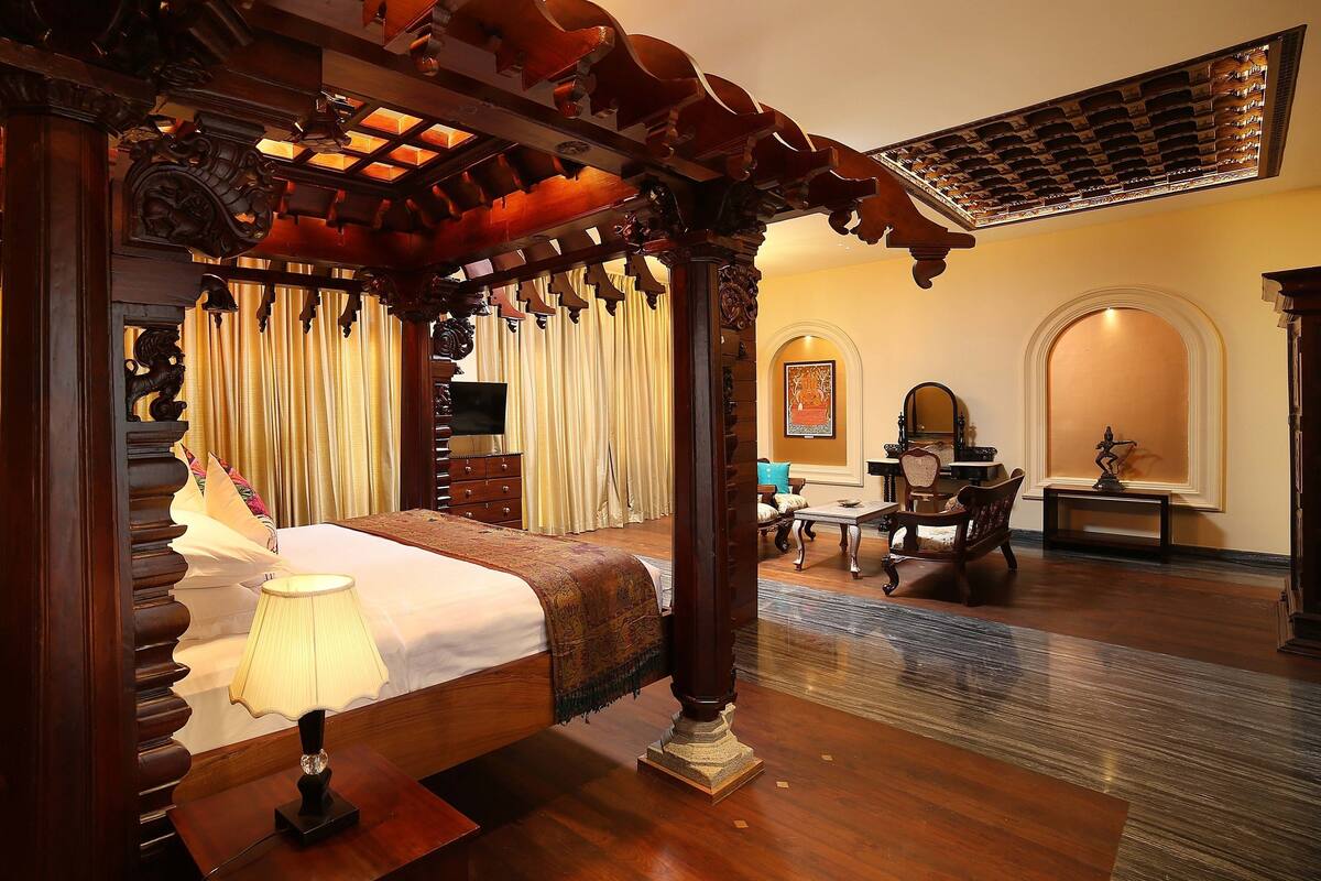A traditional room with a four-poster bed, a television, a desk, and a mirror.