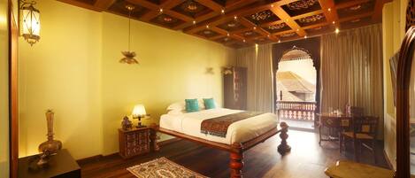 A traditional room with a wooden bed, a nightstand, a lamp, and a view of the outside balcony.