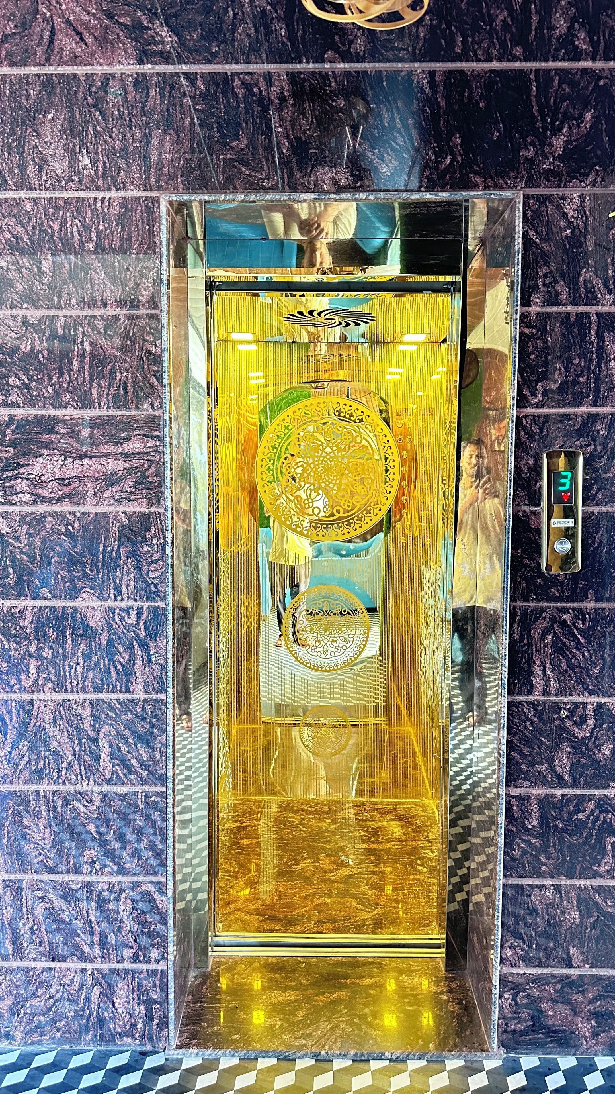 Um elevador com interior espelhado e um visor digital indicando o número 3.
