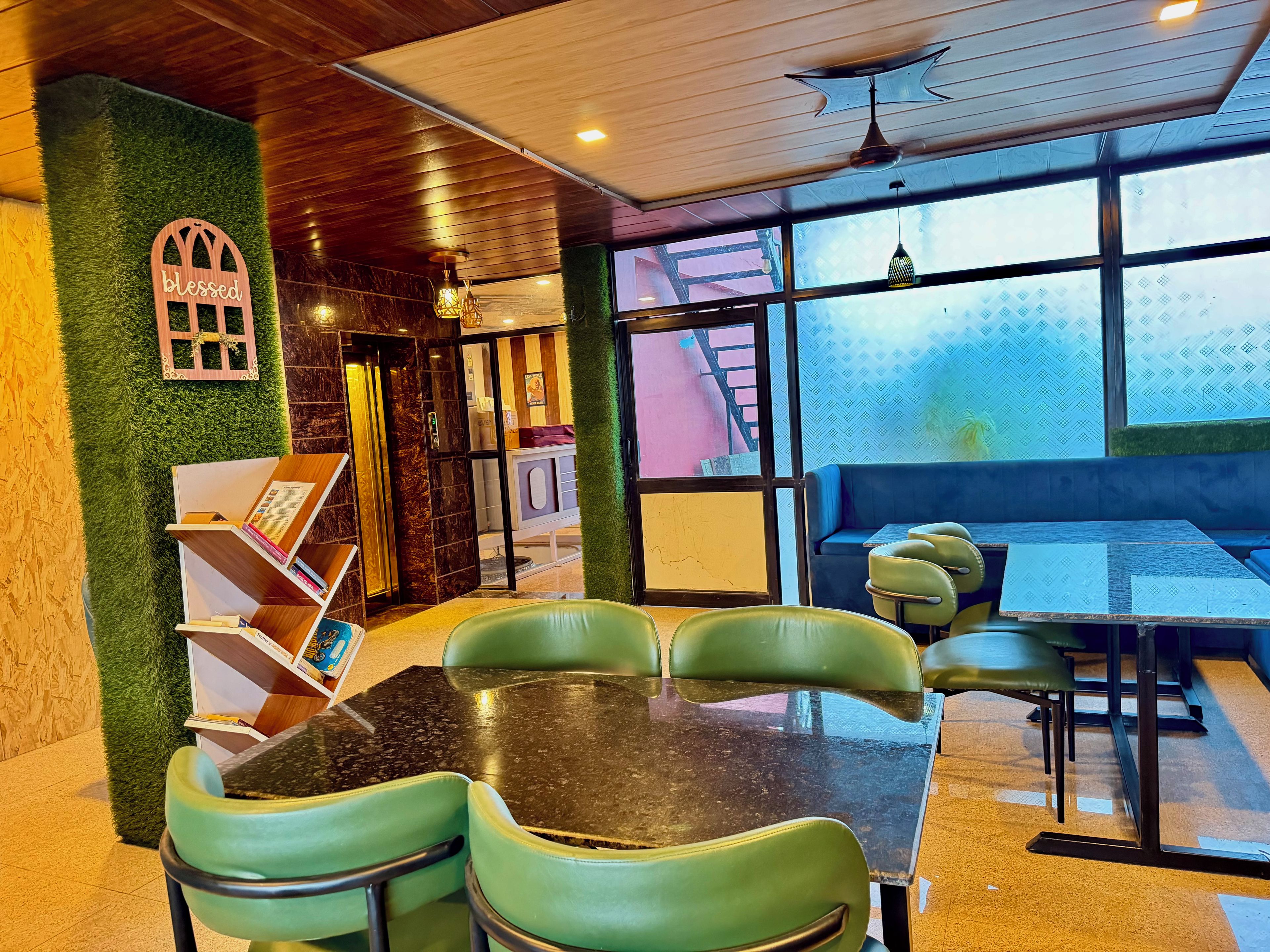 Interior de restaurante com parede verde, teto de madeira e uma grande janela.