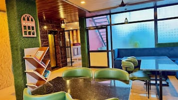 Interior de restaurante com parede verde, teto de madeira e uma grande janela.