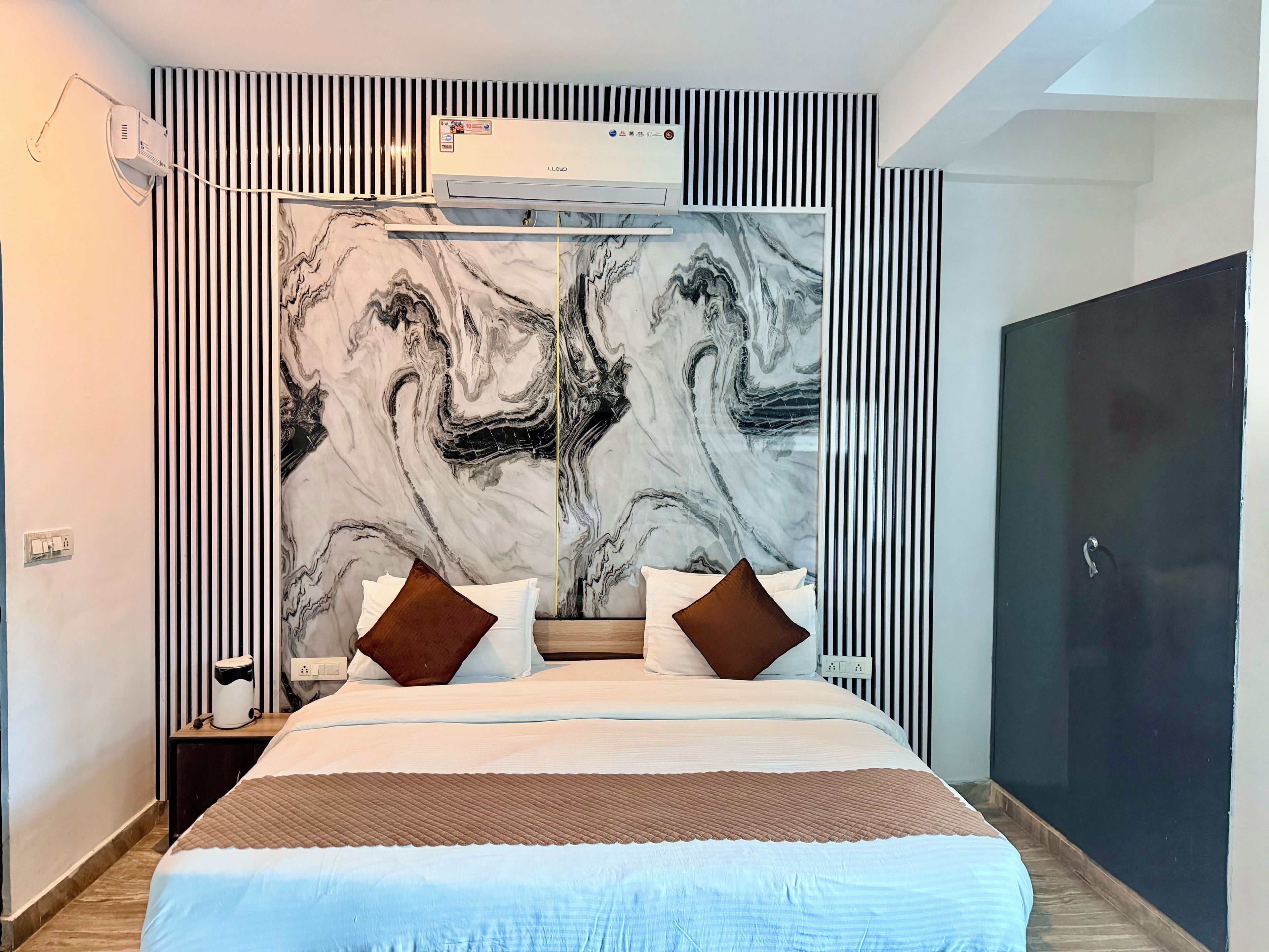 Habitación de hotel con una cama grande, cabecera con diseño de mármol, armario y aire acondicionado.