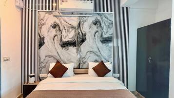 Habitación de hotel con una cama grande, cabecera con diseño de mármol, armario y aire acondicionado.