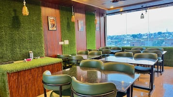 Un restaurante con pared verde, paneles de madera y vista a un paisaje urbano.