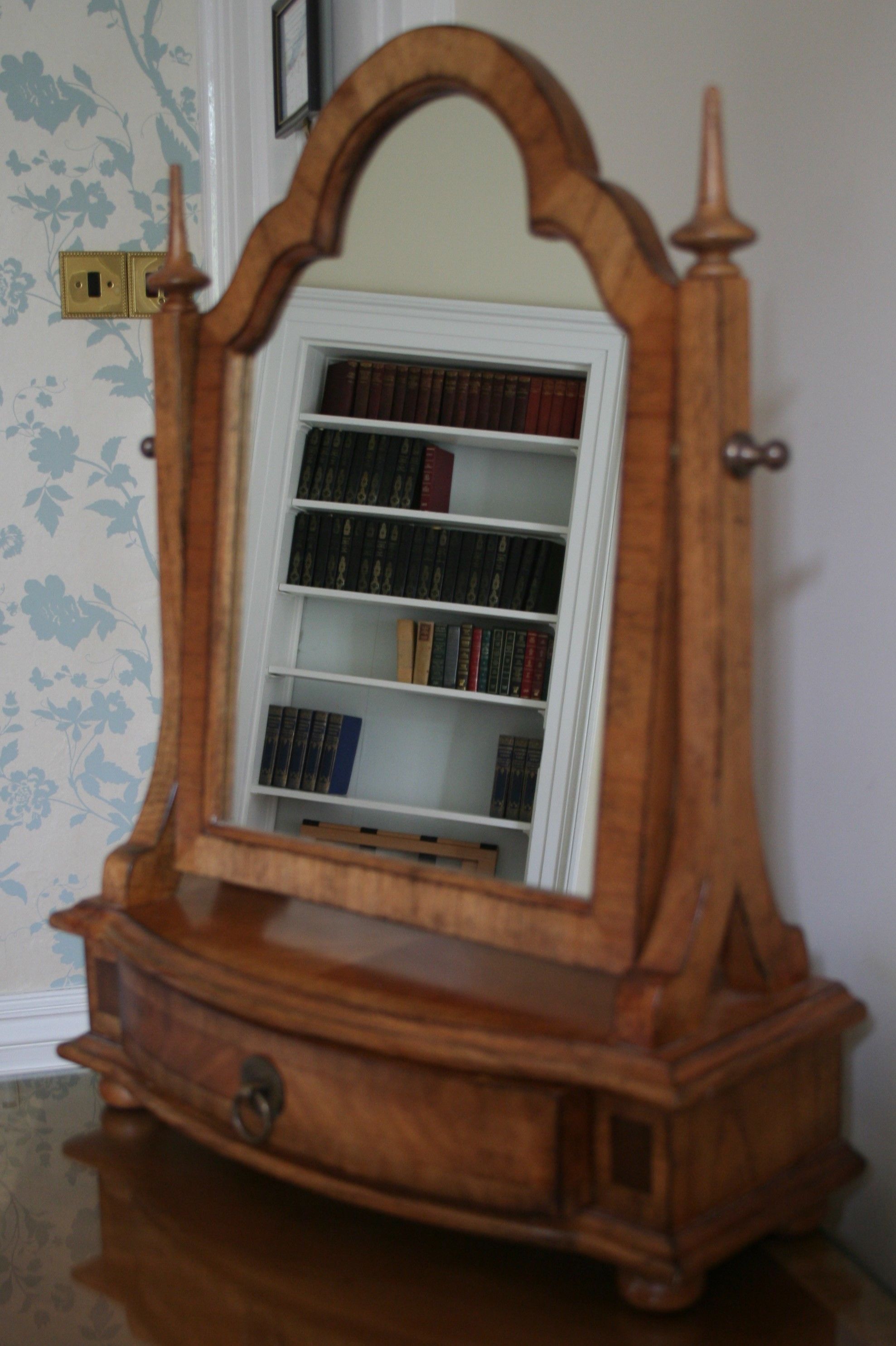 Un mueble de madera con un espejo y una estantería llena de libros.