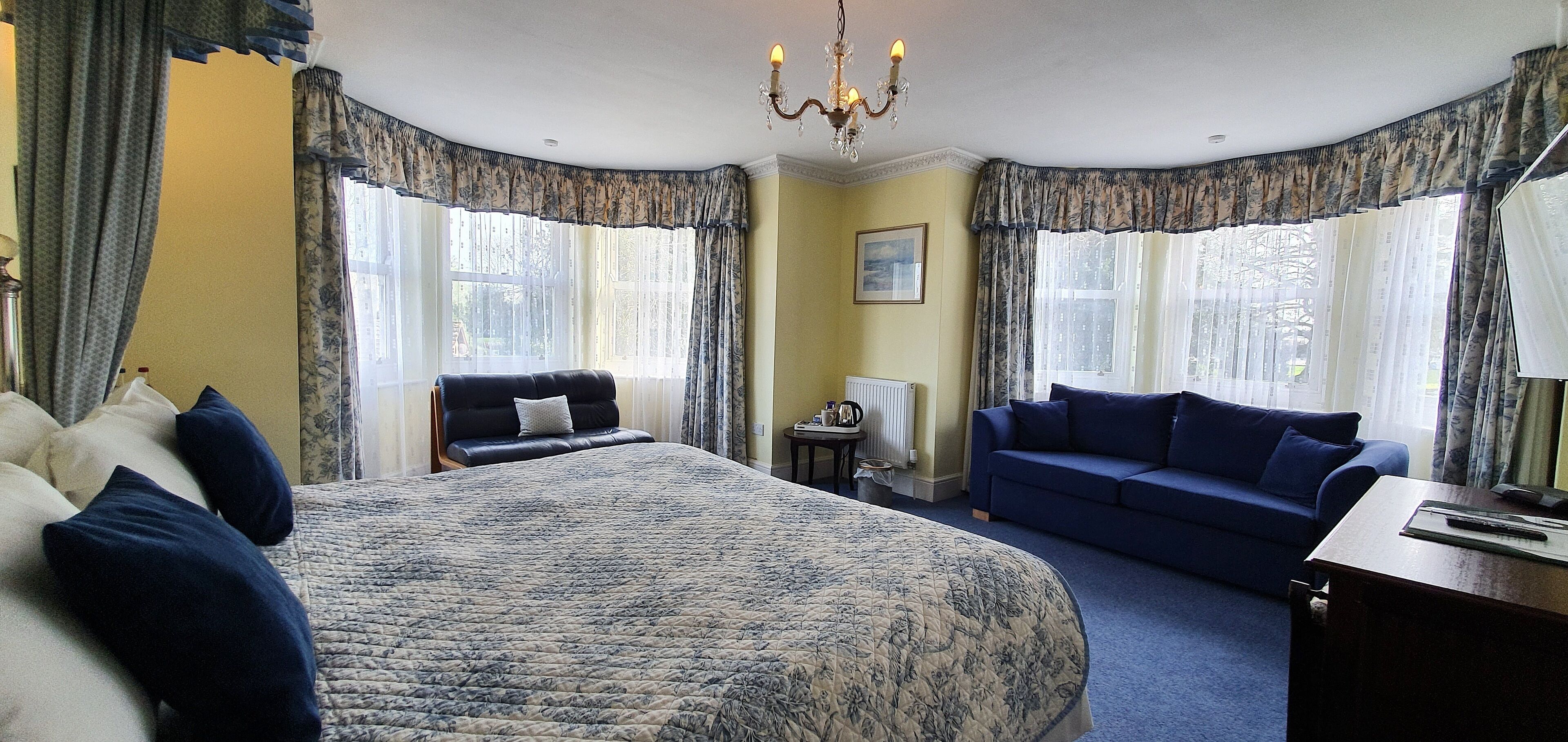 Une chambre avec un grand lit, un canapé bleu et une petite table.