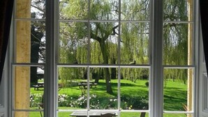 Una habitación con un ventanal grande que da a un jardín con mesas y sillas.
