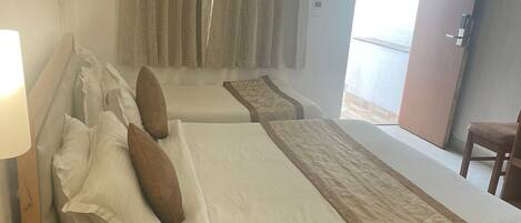 A hotel room with two beds, a bedside table with a phone, and a view of the outside.