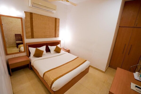 A hotel room with a large bed, a nightstand, a mirror, and wooden cabinets.