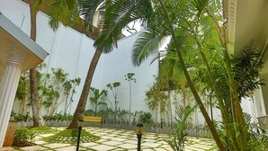A courtyard with a patterned stone floor, palm trees, and a bench. - Avenue 11 Boutique Residences (Chennai)