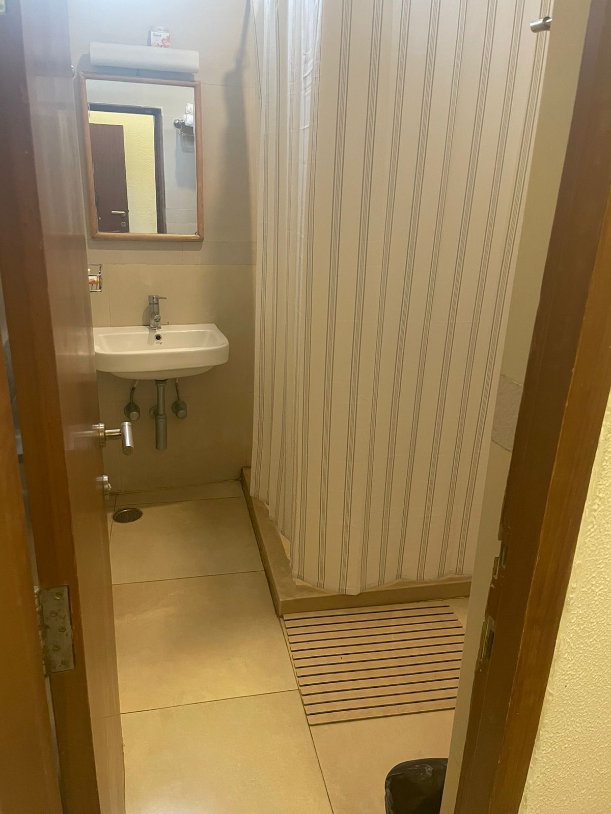 A small bathroom with a sink, mirror, and striped shower curtain.