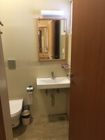 Un baño pequeño con un lavamanos blanco, un espejo, un inodoro y un cubo de basura.