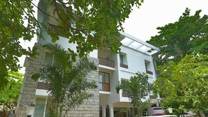 A modern multi-story building with a stone facade, balconies, and surrounding greenery. - Avenue 11 Boutique Residences (Chennai)