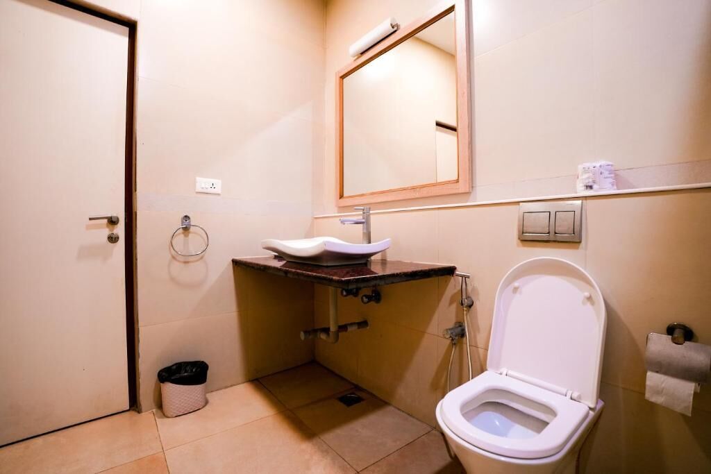 A small bathroom with a toilet, sink, and mirror.