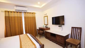 Une chambre d’hôtel équipée d’un lit, d’un bureau avec une chaise, d’une télévision et d’un appareil de climatisation.
