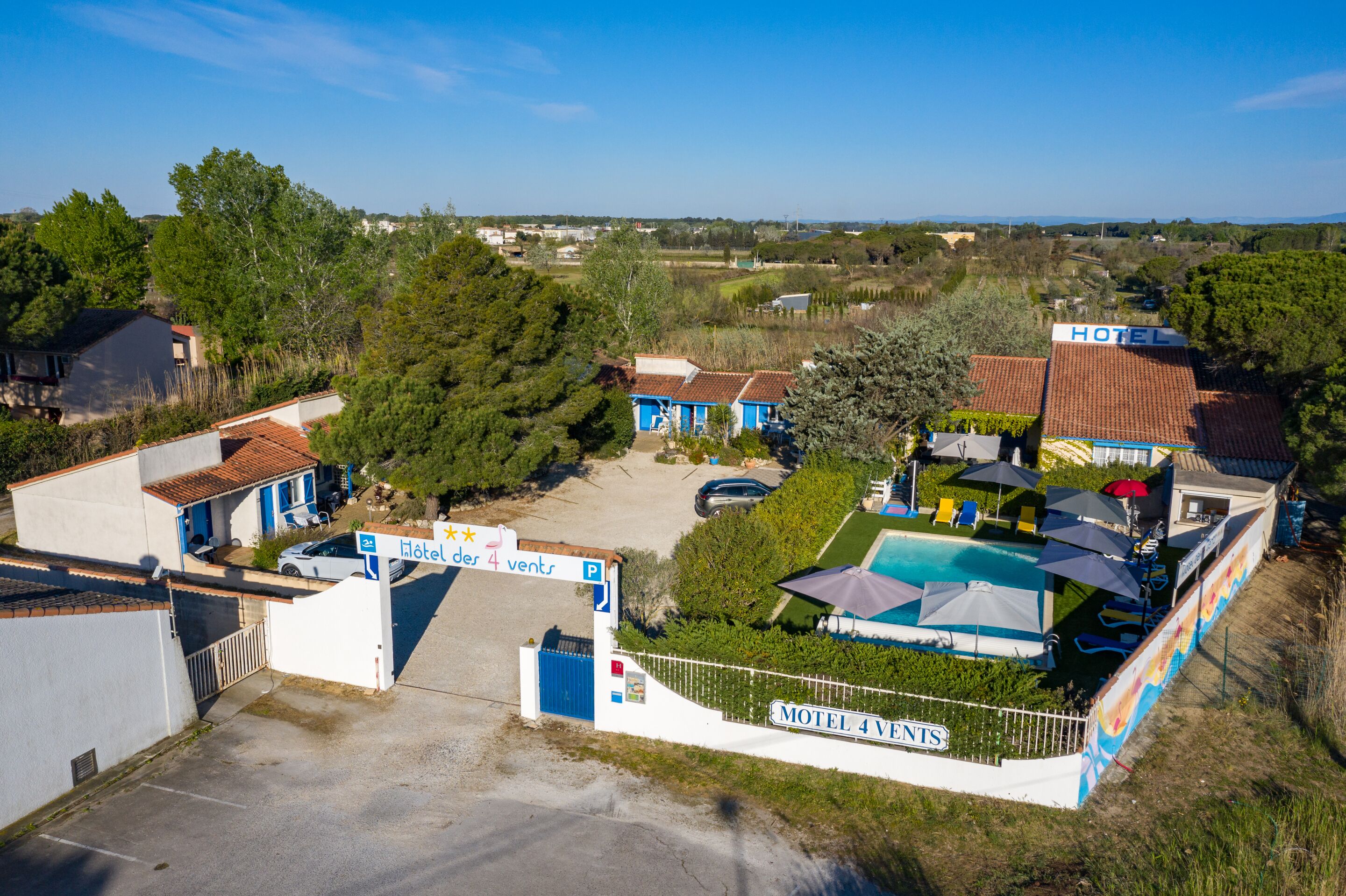 A hotel with a swimming pool, a parking area, and a sign indicating 4 available rooms.