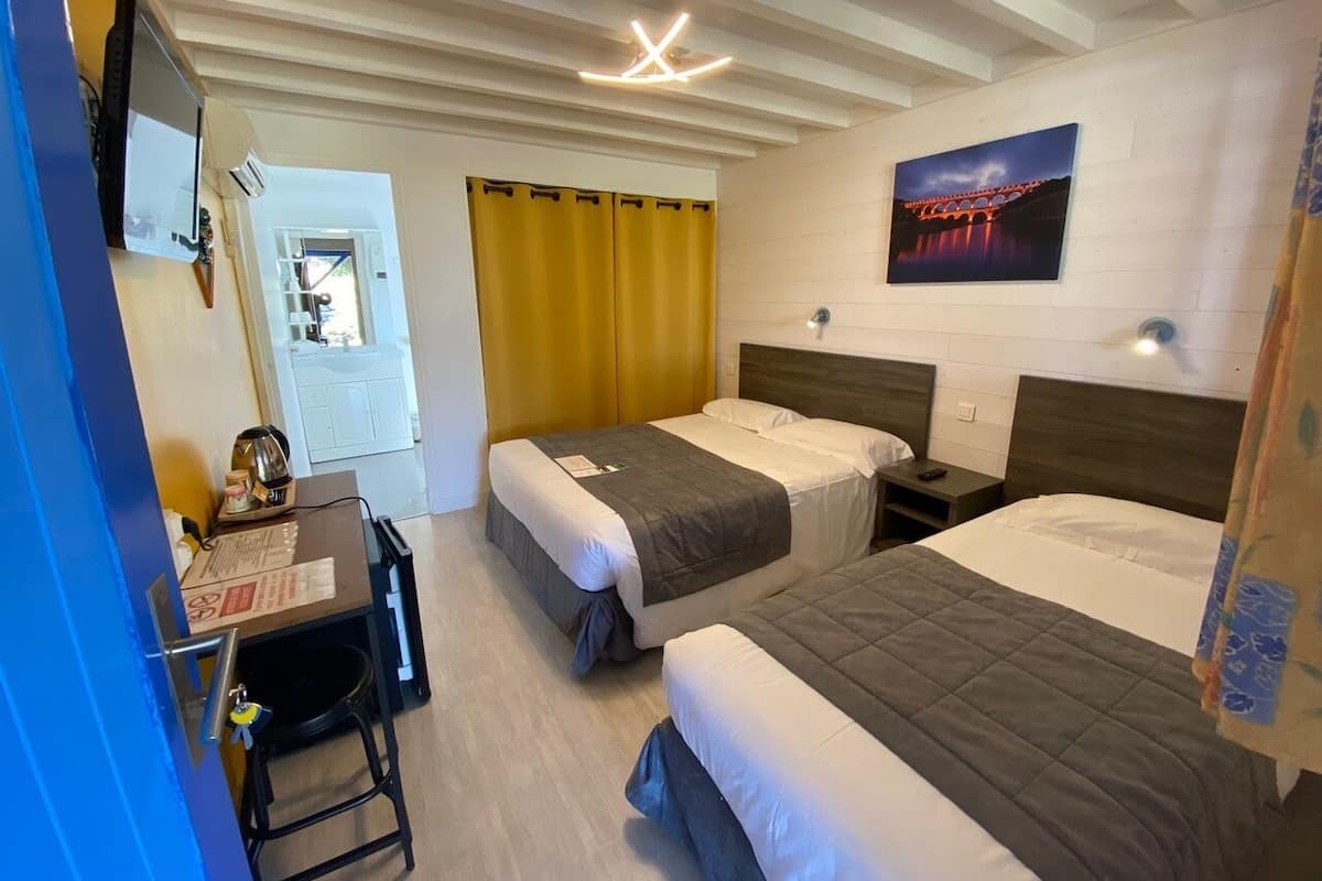 Une chambre d’hôtel avec deux lits, un bureau et une télévision.