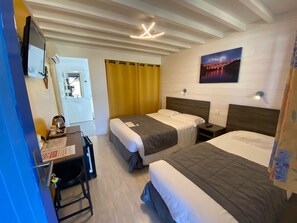 Ein Hotelzimmer mit zwei Betten, einem Schreibtisch und einem Fernseher.
