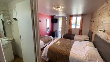 Habitación de hotel con dos camas, baño, televisor y pared de madera.