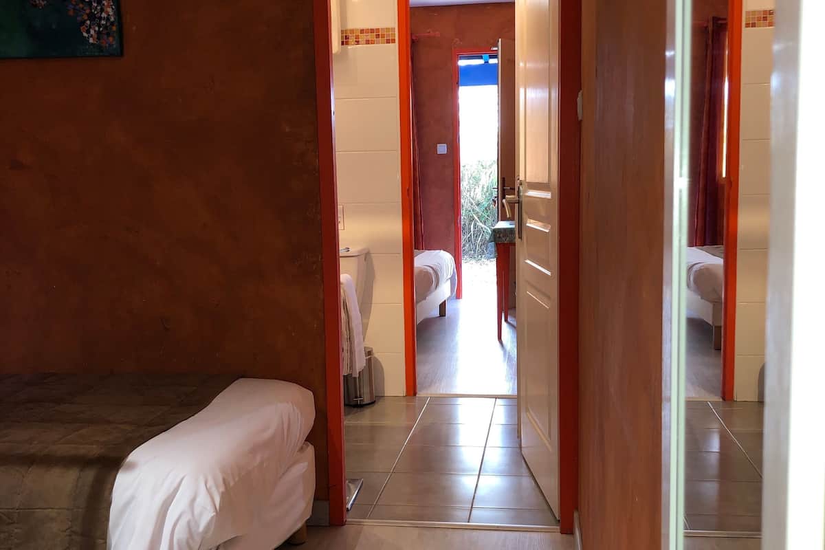 Une chambre d’hôtel avec un lit, une petite table et une vue sur la salle de bain et le couloir.