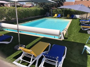 Ein Schwimmbecken mit Liegebereich, ausgestattet mit Liegestühlen und Sonnenschirmen.