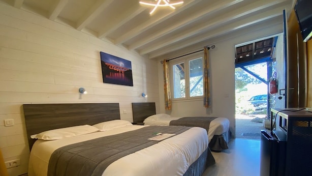 Une chambre d’hôtel avec deux lits, une télévision et une fenêtre avec des rideaux.