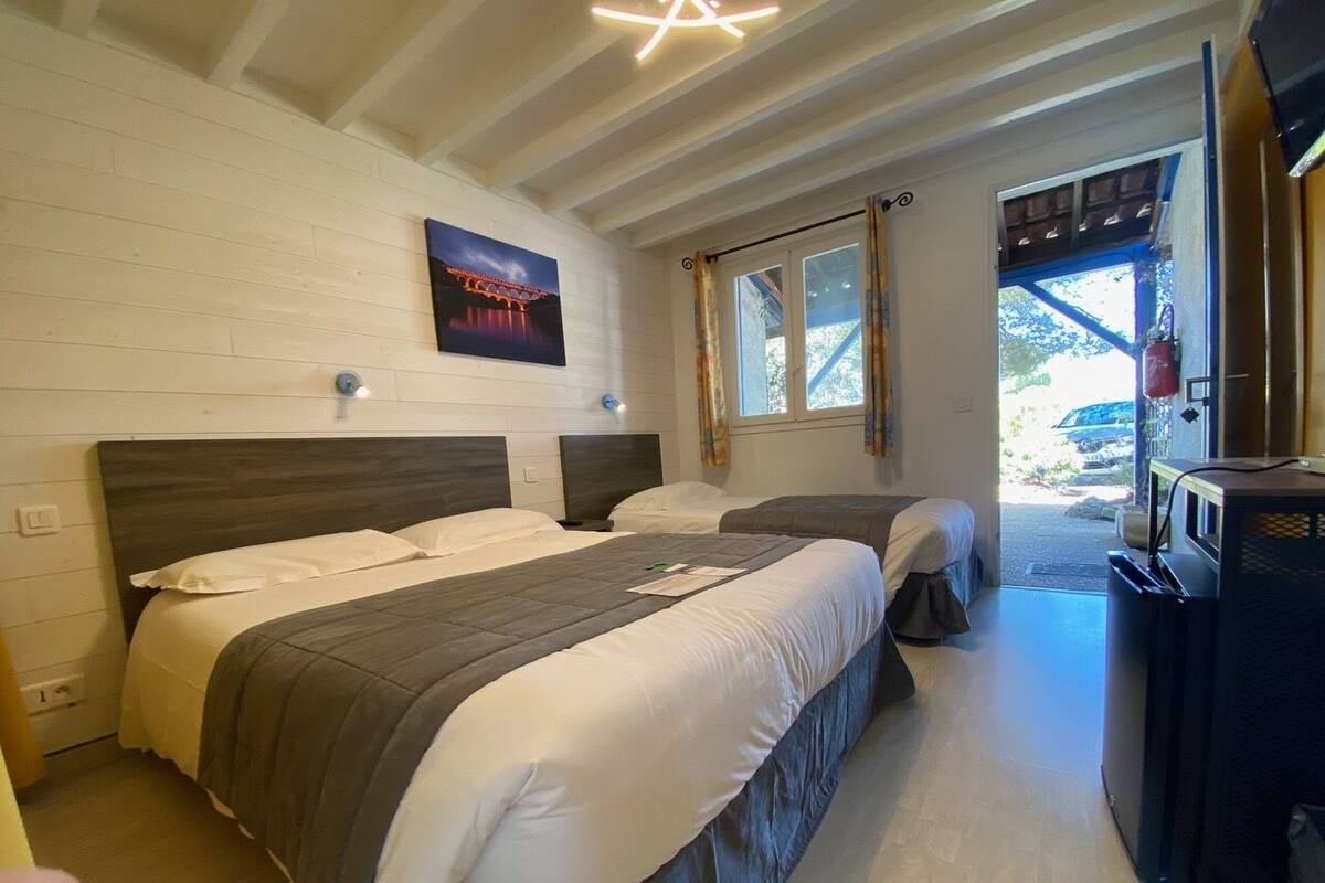 Une chambre d’hôtel avec deux lits, une télévision et une fenêtre avec des rideaux.