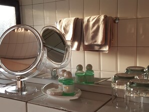 Bathroom features a large round mirror, glass-topped vanity, and sink.