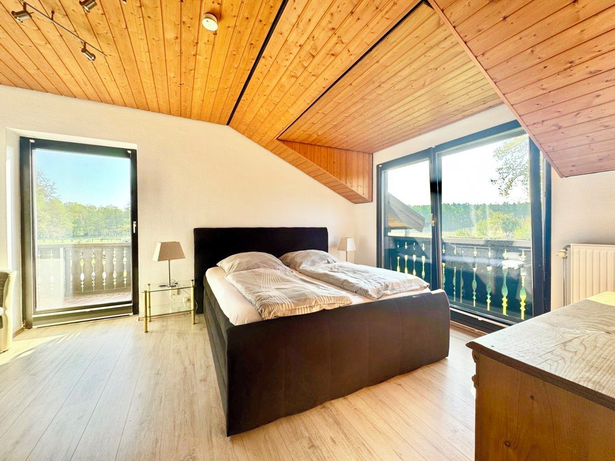 Un dormitorio con una cama grande, techo de madera y un balcón con vistas.