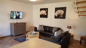 Una sala de estar con televisor, sofá, mesa de centro y obras de arte en las paredes.