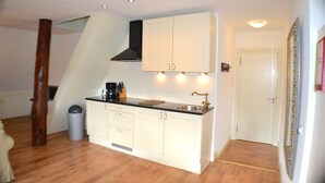 A compact kitchen with white cabinets, a black countertop, and a stainless steel sink. - Appartementenboerderij Nieuwesluis (Wieringerwaard)