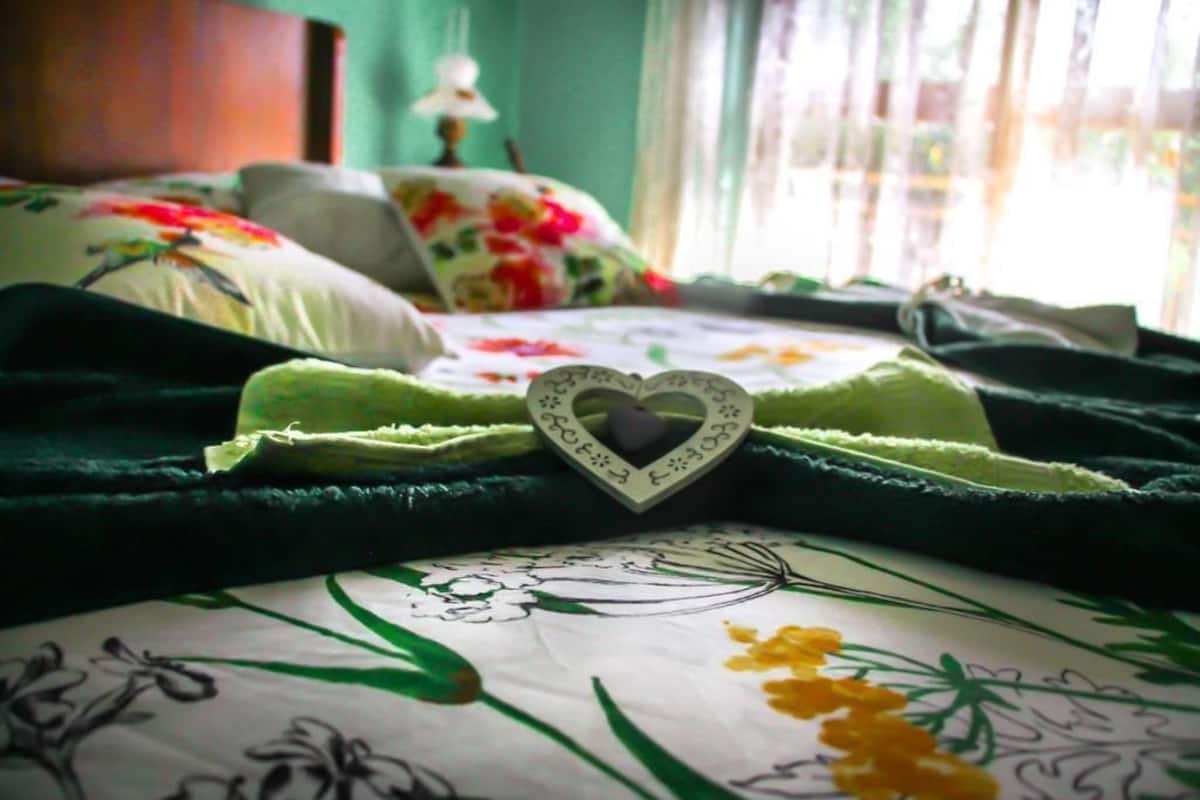 A bed with floral bedding and a heart-shaped pillow.