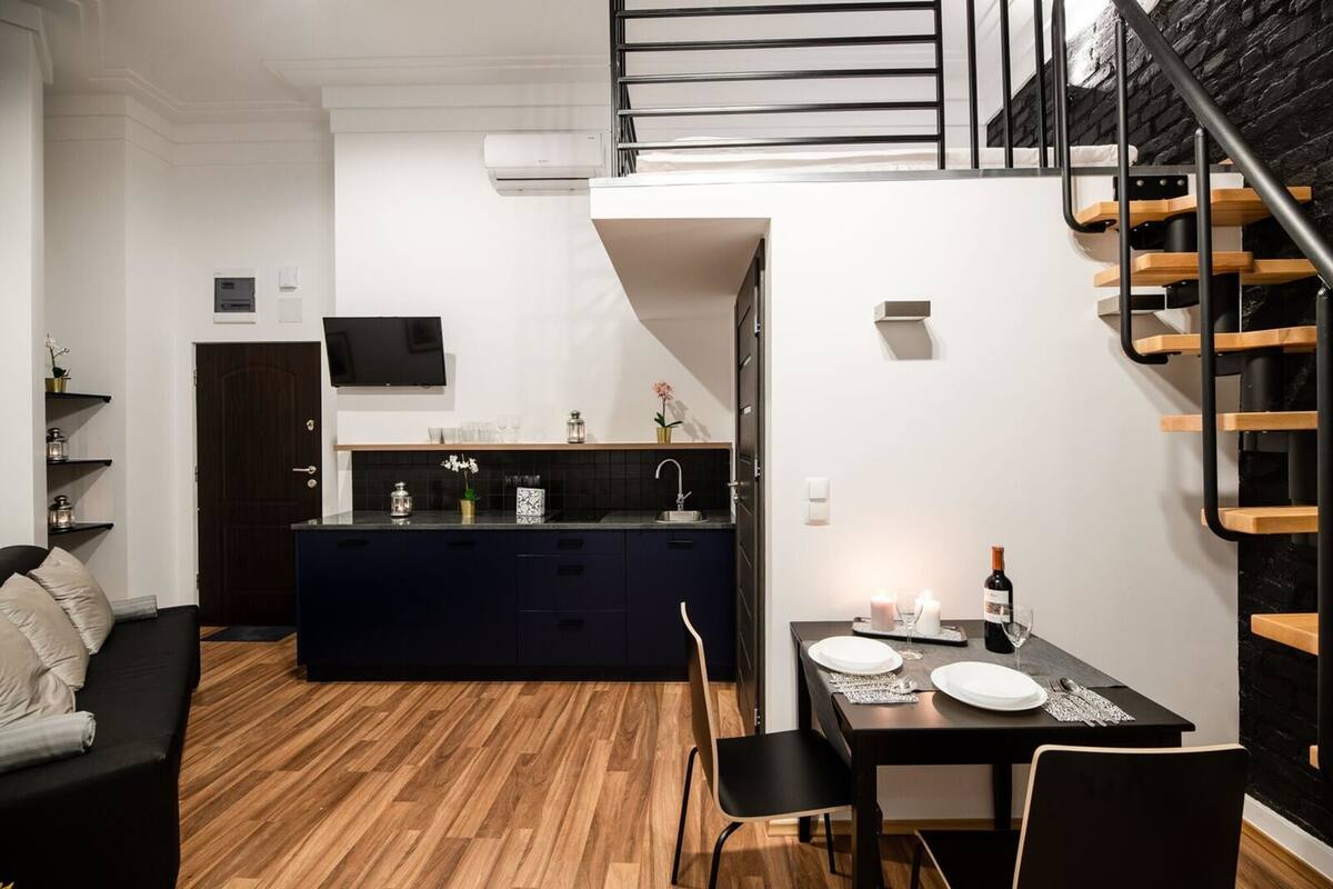 A compact living space with a kitchenette, dining area, and a staircase.
