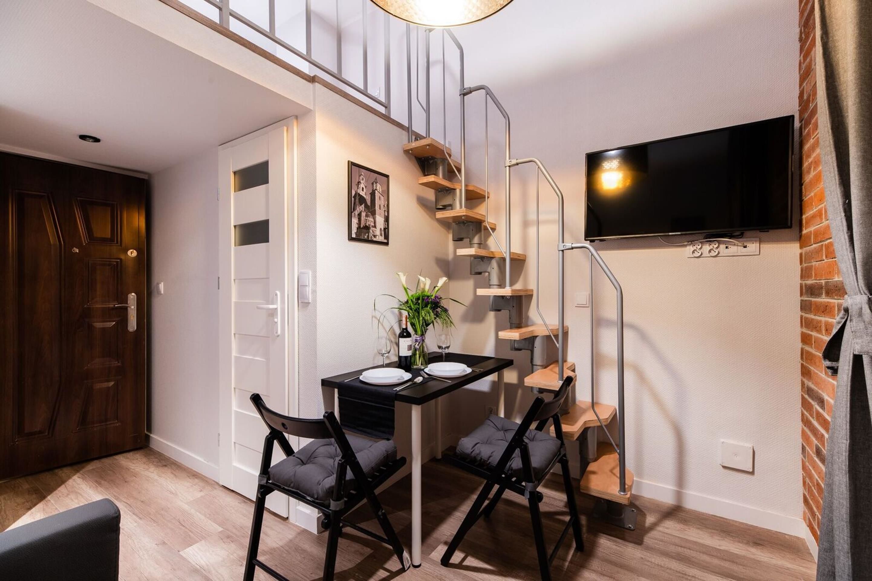 A modern kitchen with a dining table, chairs, and a staircase leading to an upper level.
