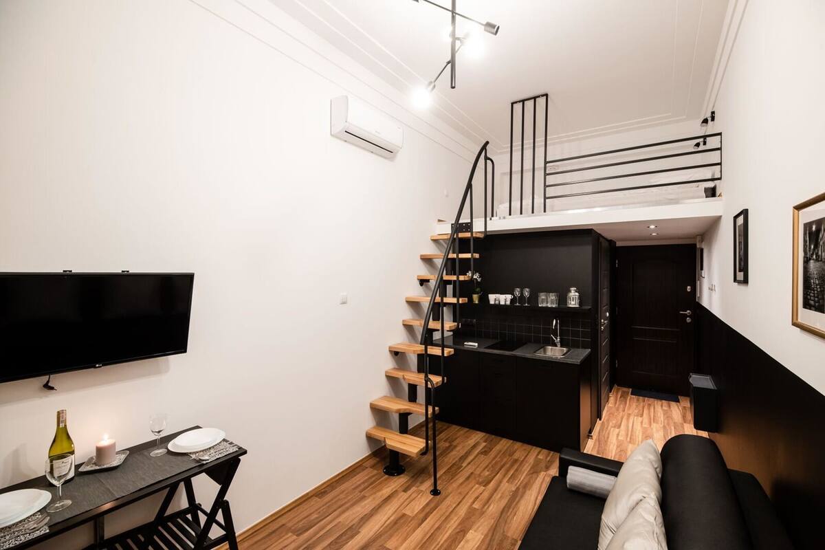 A compact living space with a kitchen, a dining area, and a staircase to a loft.