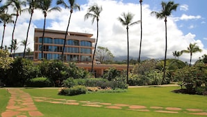 A well-maintained garden with a stone pathway leading to a building with multiple floors and large windows. - Maui Kaanapali S #e290 Studio Bedroom Condo by RedAwning (Lahaina)
