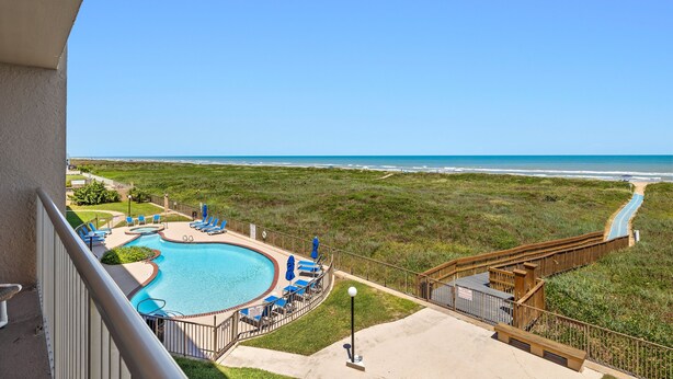 A pool area with a view of the beach and ocean.