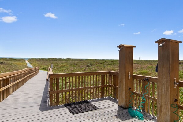 A wooden boardwalk leading to a beach with a clear sky.