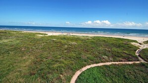 Un paisaje costero con playa, zonas verdes y cielo despejado.