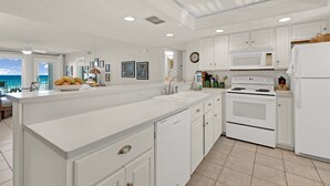 Una cocina moderna con armarios blancos, una isla central, microondas, estufa y refrigerador.