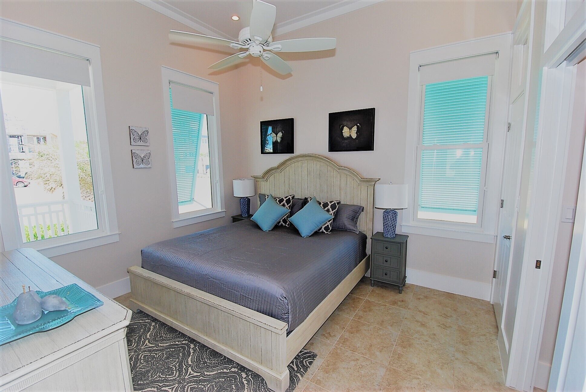 A bedroom with a bed, two bedside tables, a ceiling fan, and a window with blinds.