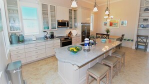 Una cocina moderna con una isla central, electrodomésticos de acero inoxidable y una zona de comedor con sillas de madera.